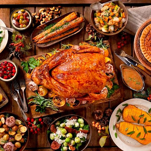 This image shows a Thanksgiving spread with roast turkey, various vegetables, salads, bread, pie, and assorted side dishes on a wooden table.